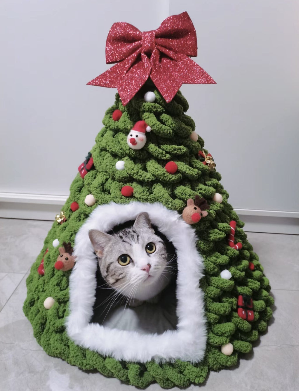 Gato dentro de la cueva decorada como arbol de Navidad